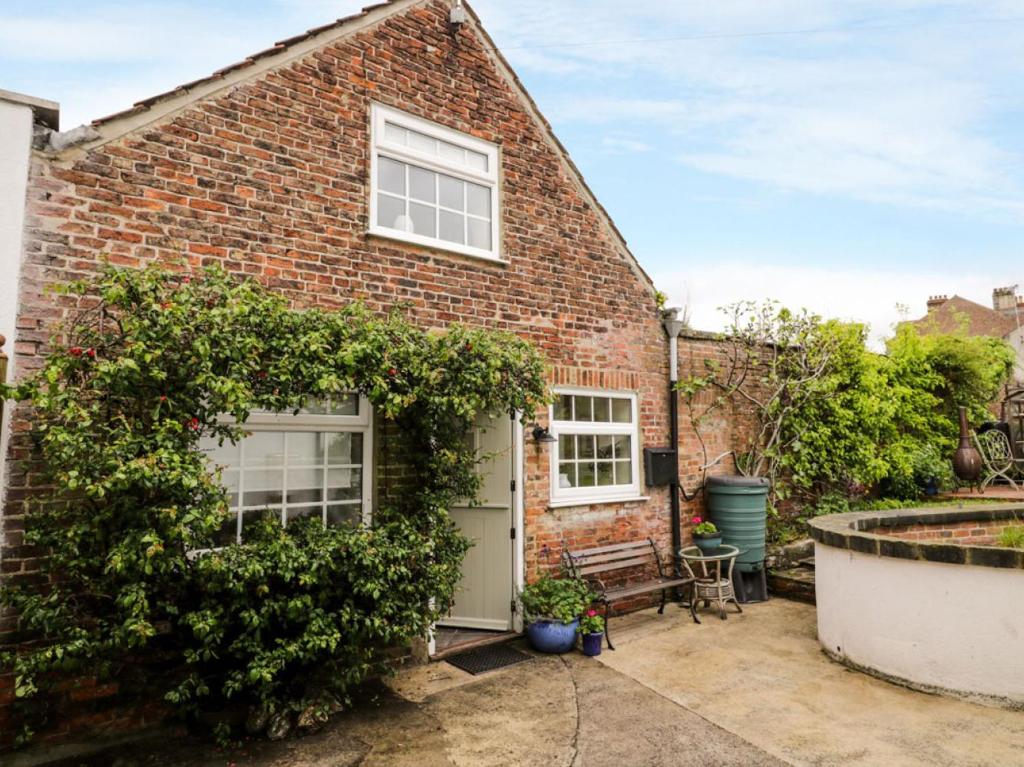 une maison en briques avec une porte blanche et un jardin dans l'établissement October Cottage, à Ripon