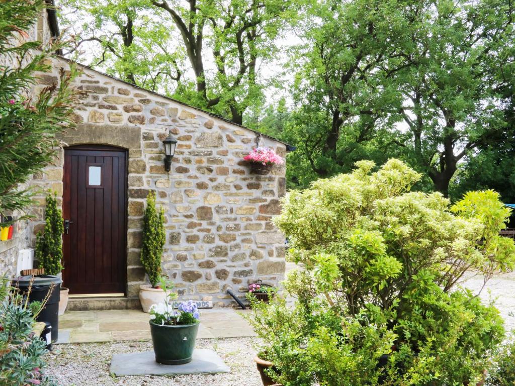 a stone house with a wooden door in a garden at Woodlands in Halton West