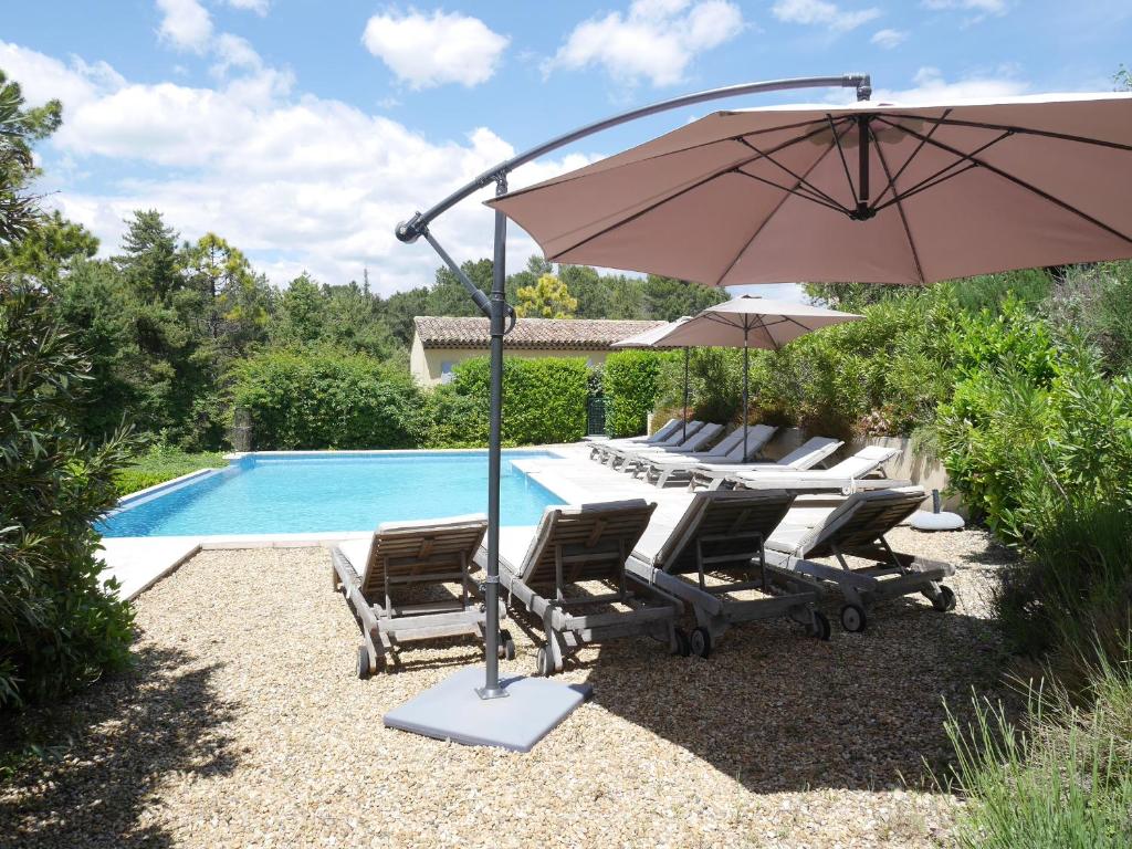 um grupo de cadeiras e um guarda-sol junto a uma piscina em Villa Verdi em Montauroux