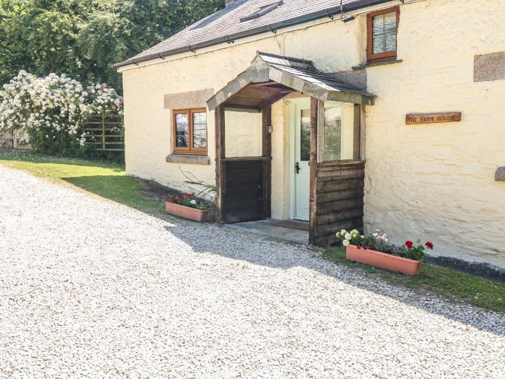 a white building with a door and some flowers at Lower West Curry Farmhouse in Launceston