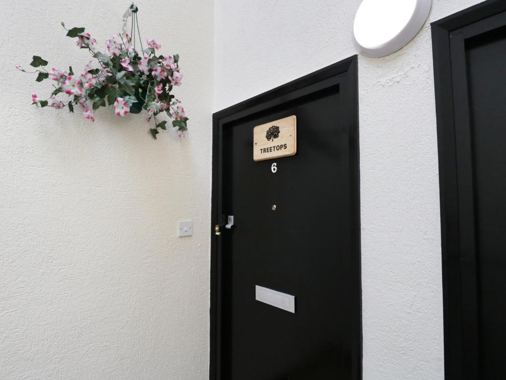 een zwarte deur met een bord naast een plant bij Treetops in Windermere