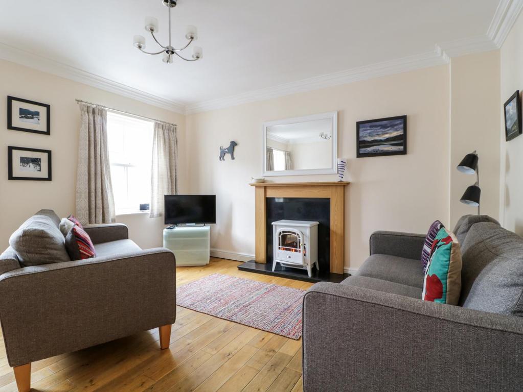 a living room with two couches and a fireplace at Siskin in Keswick