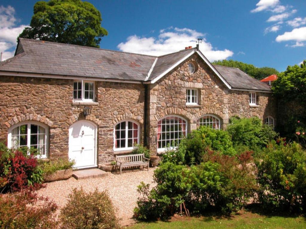 une maison en pierre avec un banc dans un jardin dans l'établissement The Coach House, à Lydford