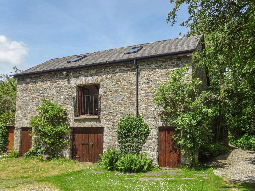 uma antiga casa de pedra com portas de madeira e um portão em Townend Barn em Lydford