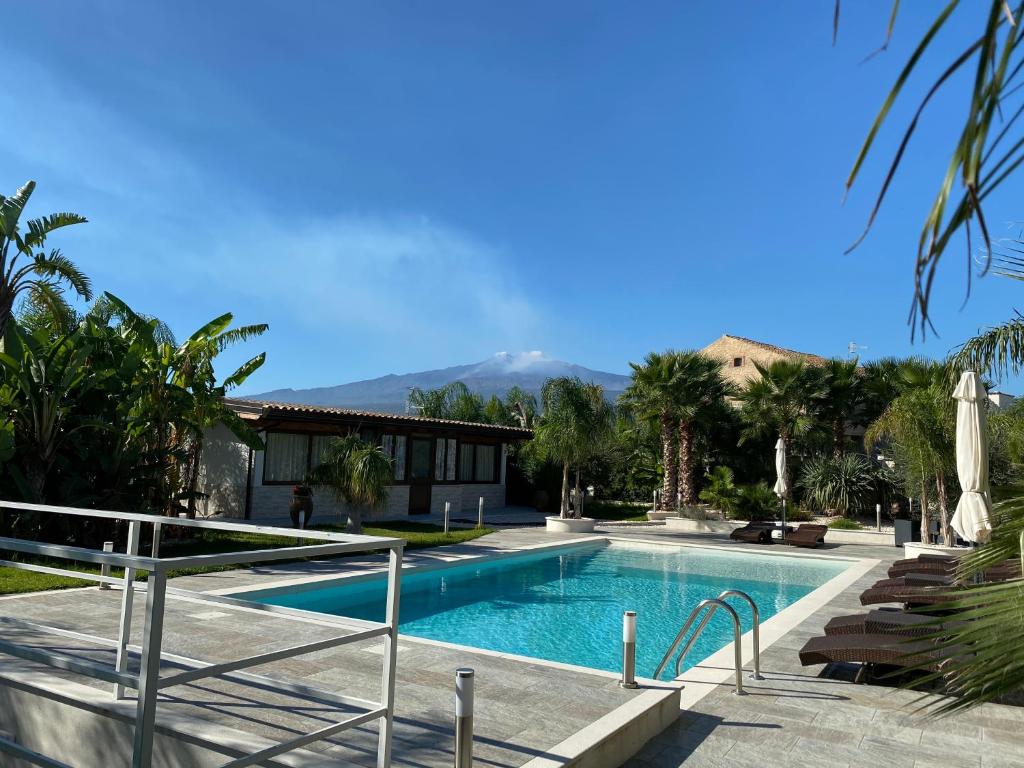 una piscina con una casa e montagne sullo sfondo di VILLA SICILIA a Calatabiano