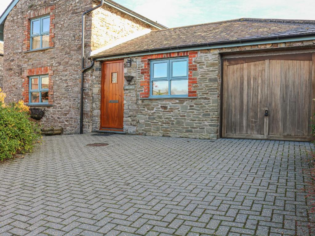 a brick house with a garage and a door at Pillars in Wrafton