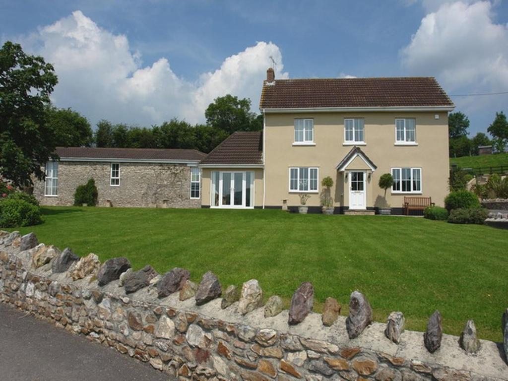 a house with a large yard with a stone wall at Lower Wadden Farmhouse and Annexe in Southleigh