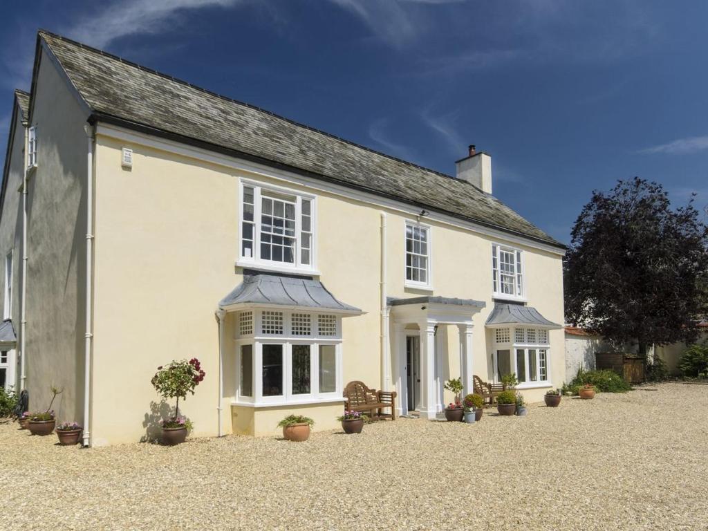 uma casa branca com vasos de plantas em frente em Abbots Manor em Honiton