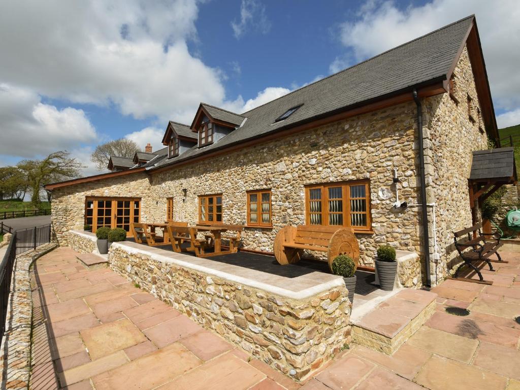 a stone house with a stone wall and a patio at The Barn in Southleigh