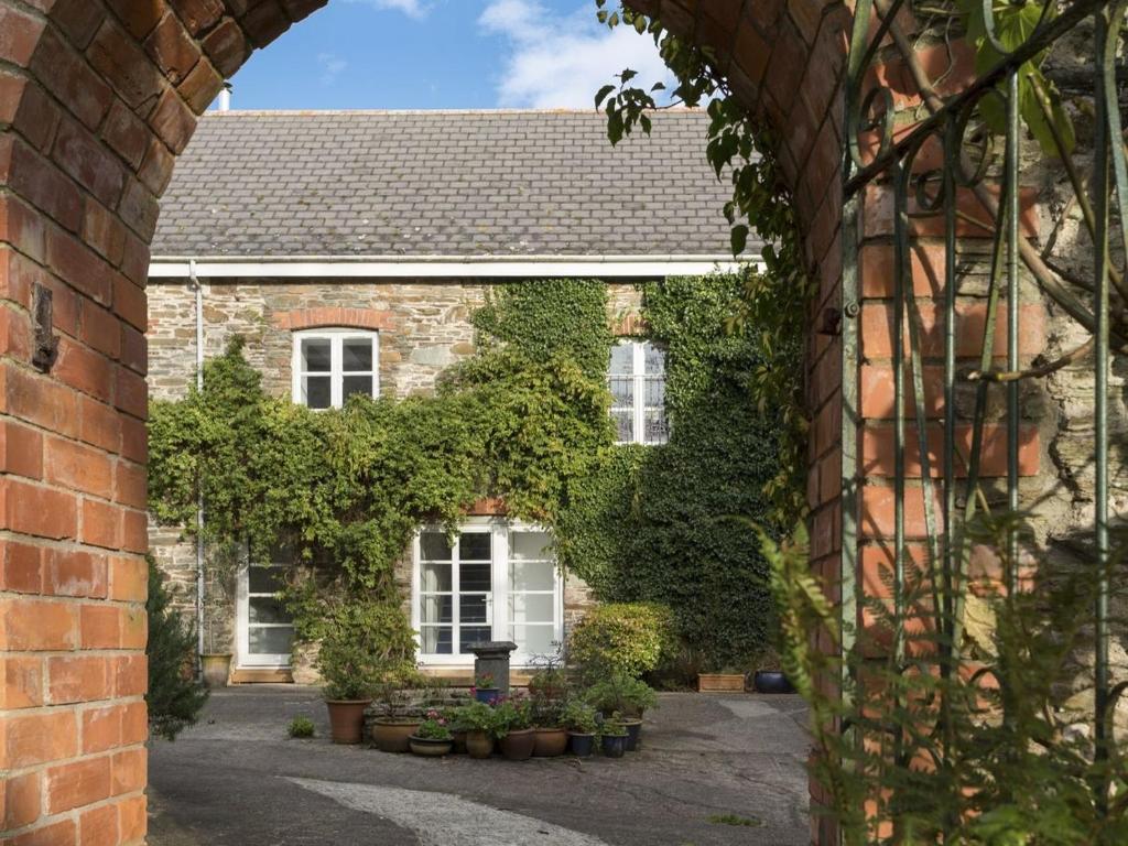 an archway in front of a brick house with plants at The Gallery in Loddiswell