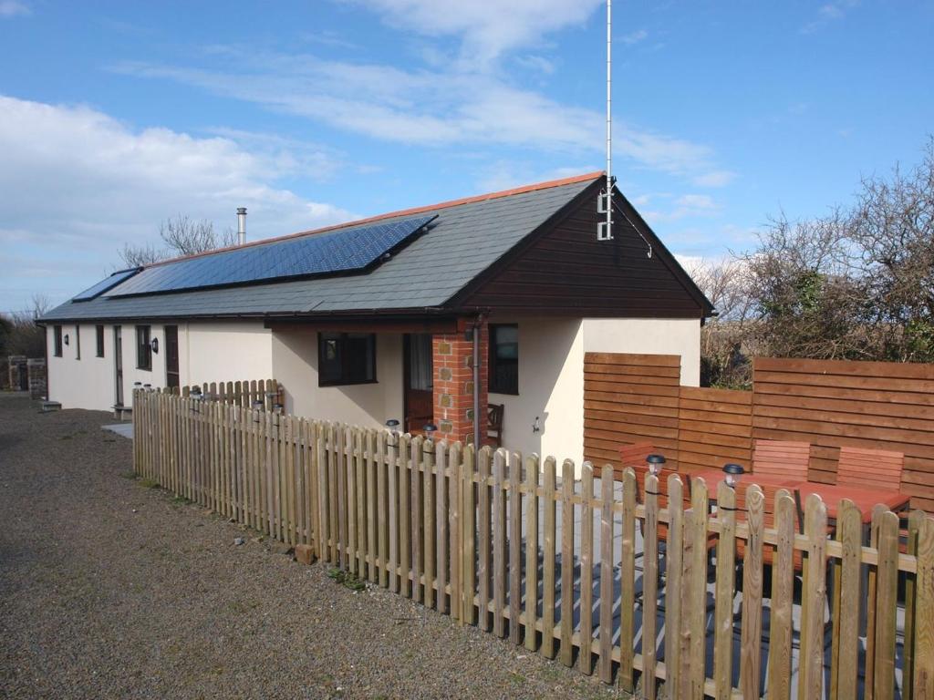 une maison avec des panneaux solaires derrière une clôture dans l'établissement Barn View, à Welcombe
