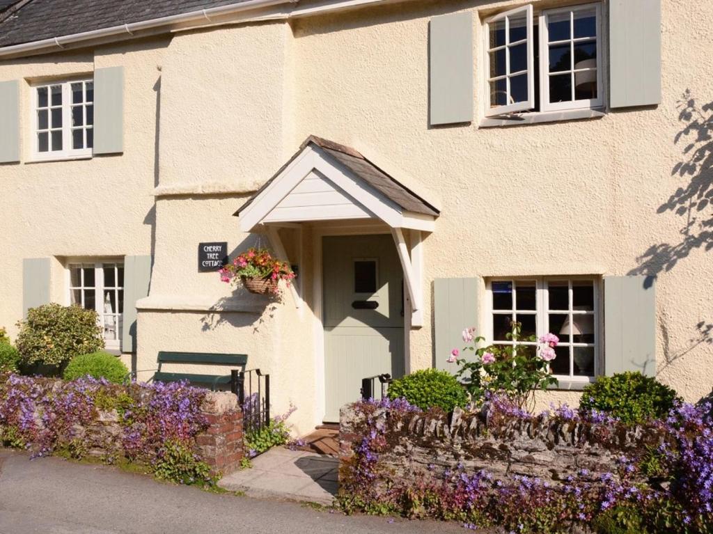 een huis met bloemen ervoor bij Cherry Tree Cottage in Noss Mayo