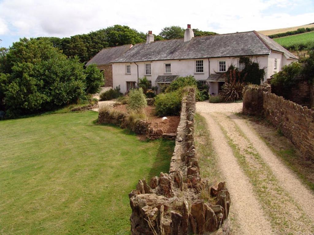 una casa con una valla de piedra frente a un patio en East Bickleigh en Totnes