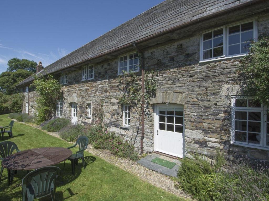 a stone building with a table and chairs and a white door at Tom in Bodmin