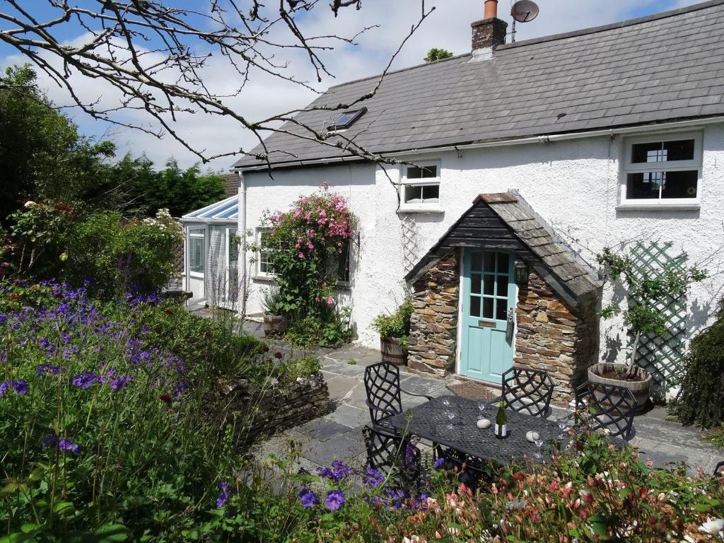 een wit huisje met een bank in de tuin bij Mays Cottage in Saint Issey