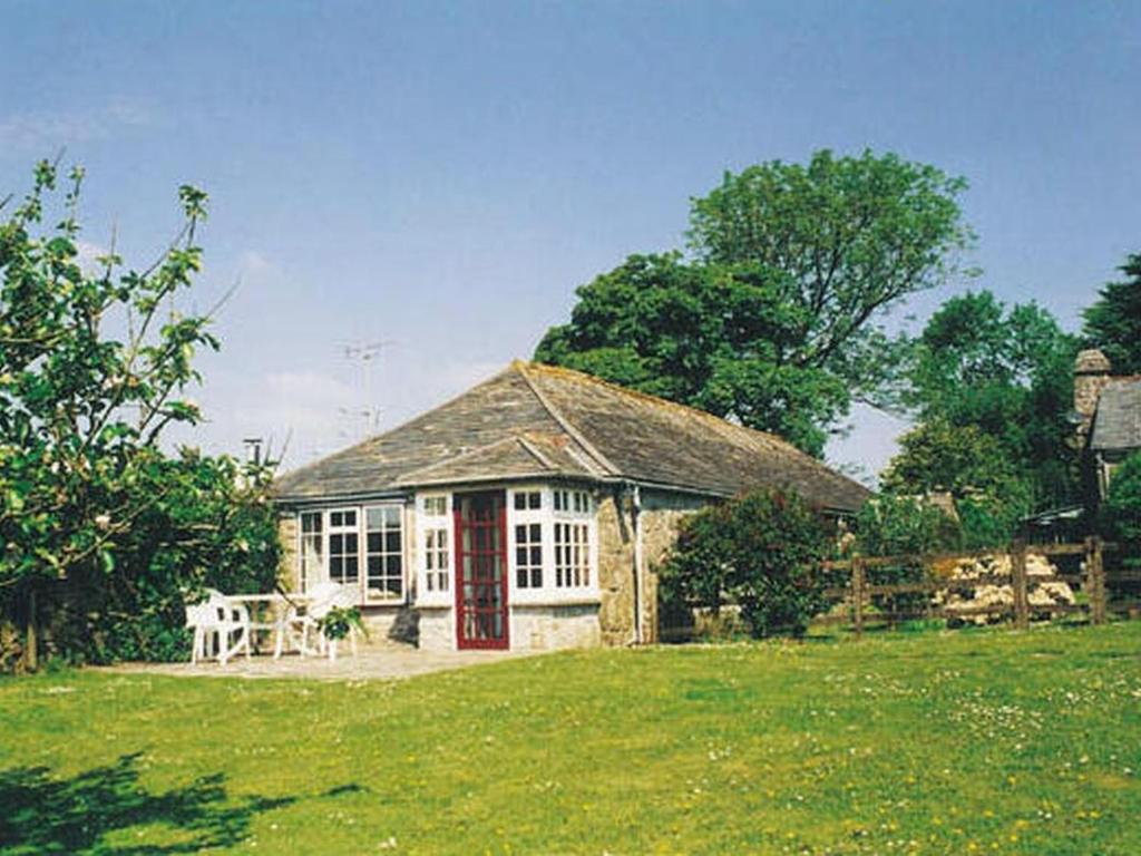 mały dom z czerwonymi drzwiami na polu w obiekcie Tumrose Cottage w mieście Blisland