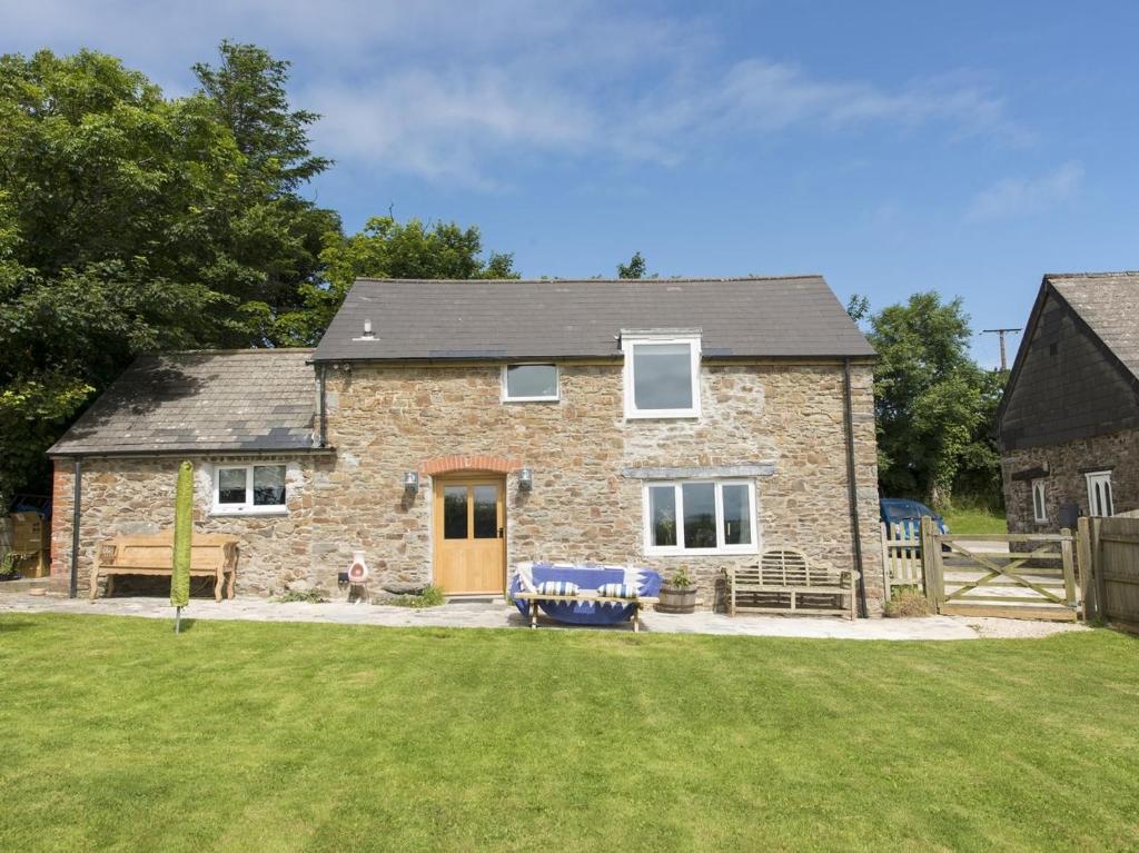 a brick house with a bench in a yard at Salty Cottage in Morwenstow