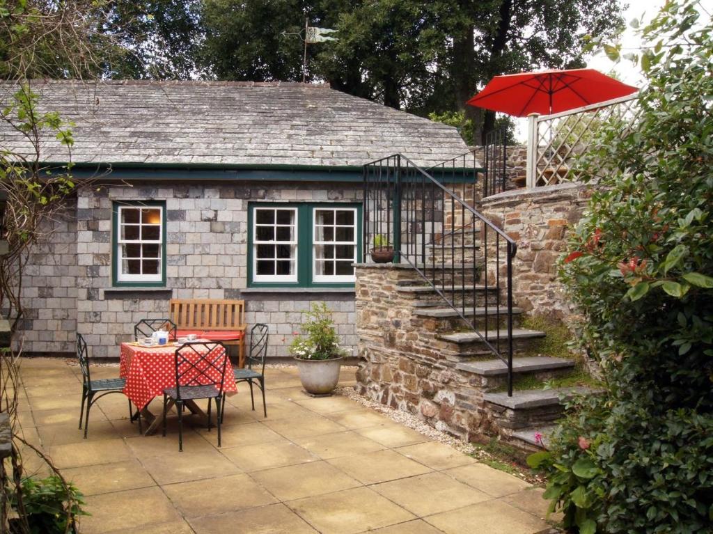 a patio with a table and a red umbrella at Grooms Cottage in Saint Minver