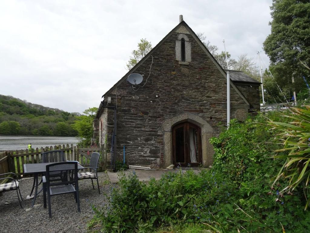 une ancienne église en pierre avec une table et des chaises dans l'établissement The Boat House, à Lerryn