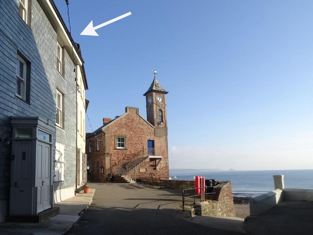 a building with a clock tower next to the ocean at Nirvana in Cawsand