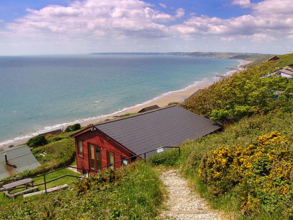 a red house on a hill next to the beach at Seagulls Nest in Cawsand