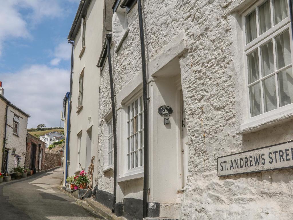 a white stone building with a street sign on it at Cousham Cottage in Cawsand