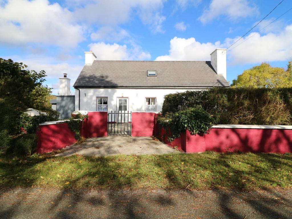 una casa bianca con una recinzione rossa davanti di Julie's Cottage a Castleisland
