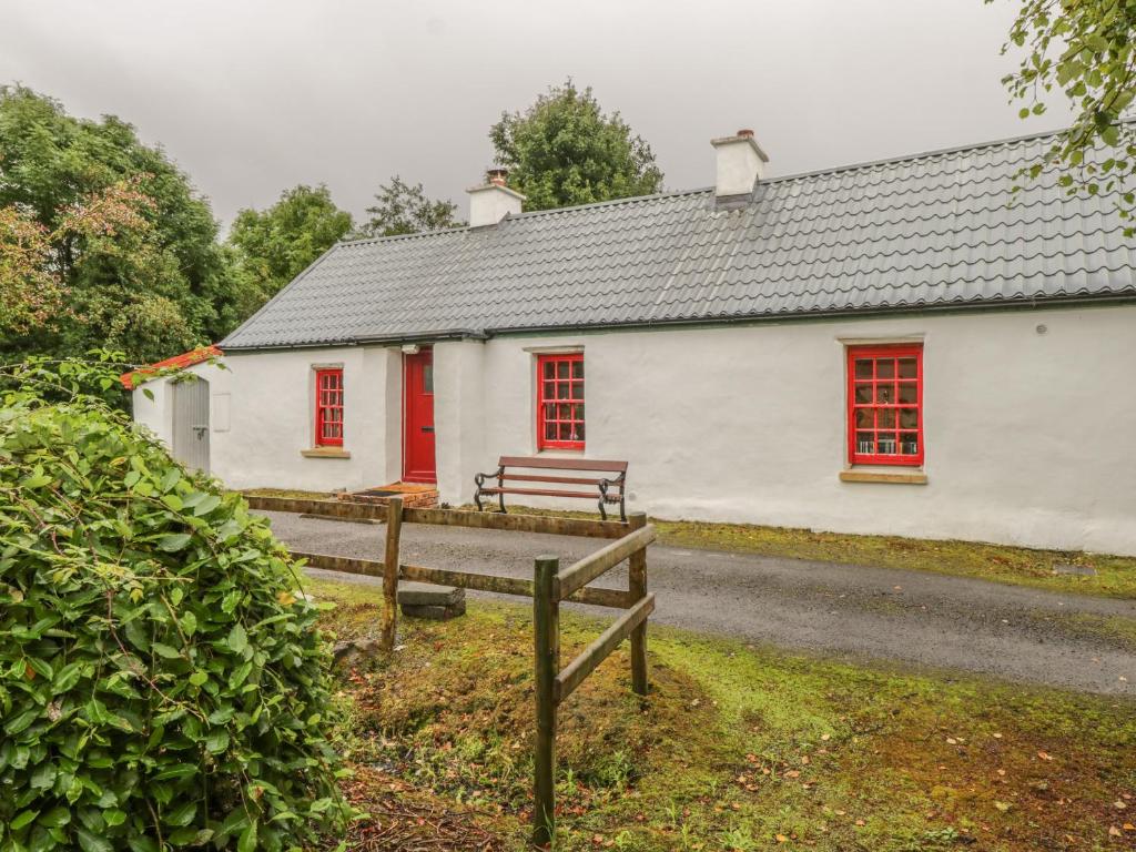 a white building with red windows and a street at Willowbrook Cottage in Ballyshannon