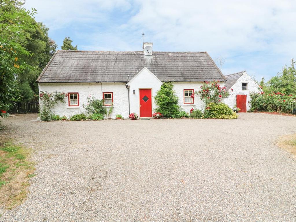 a white house with a red door on a driveway at O'Neill's in Tipperary