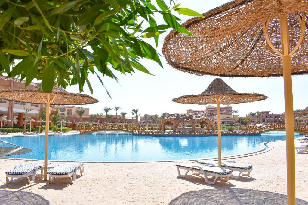 a pool with chairs and umbrellas in a resort at Parrotel Lagoon Waterpark Resort in Sharm El Sheikh