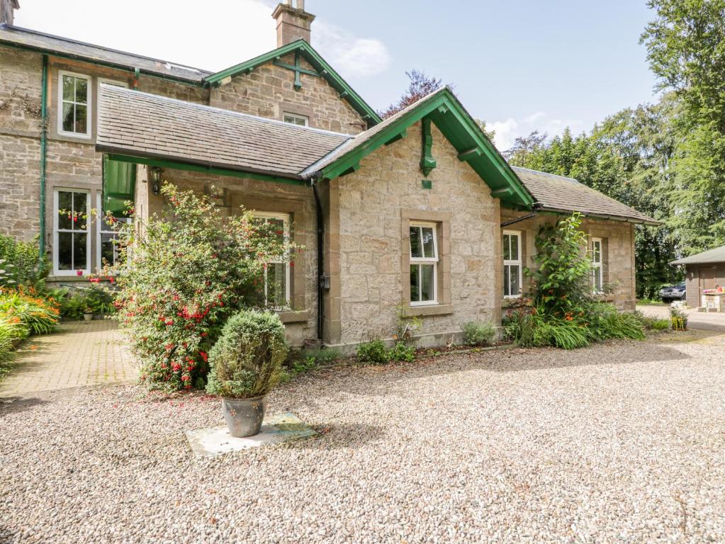 an old stone house with a gravel driveway at Courtyard Cottage in Letham