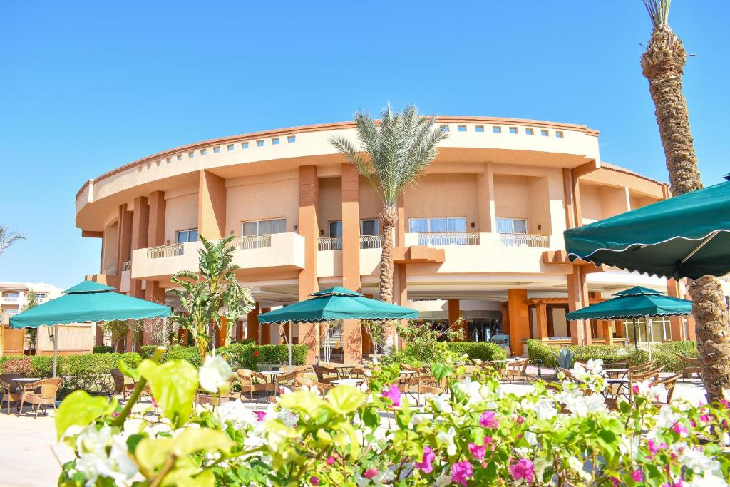 a hotel with tables and umbrellas in front of it at Parrotel Lagoon Waterpark Resort in Sharm El Sheikh