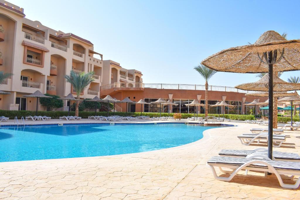 a swimming pool with lounge chairs and an umbrella at Parrotel Lagoon Waterpark Resort in Sharm El Sheikh