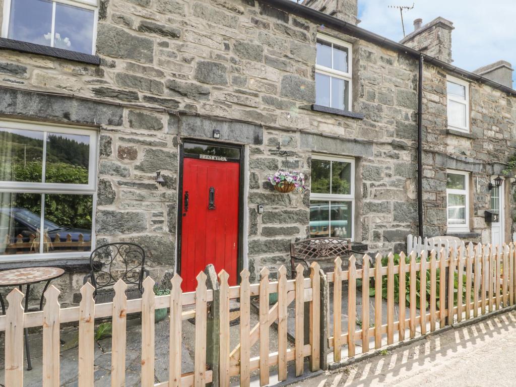 a red door on a stone house with a fence at Preswylfa in Betws-y-coed