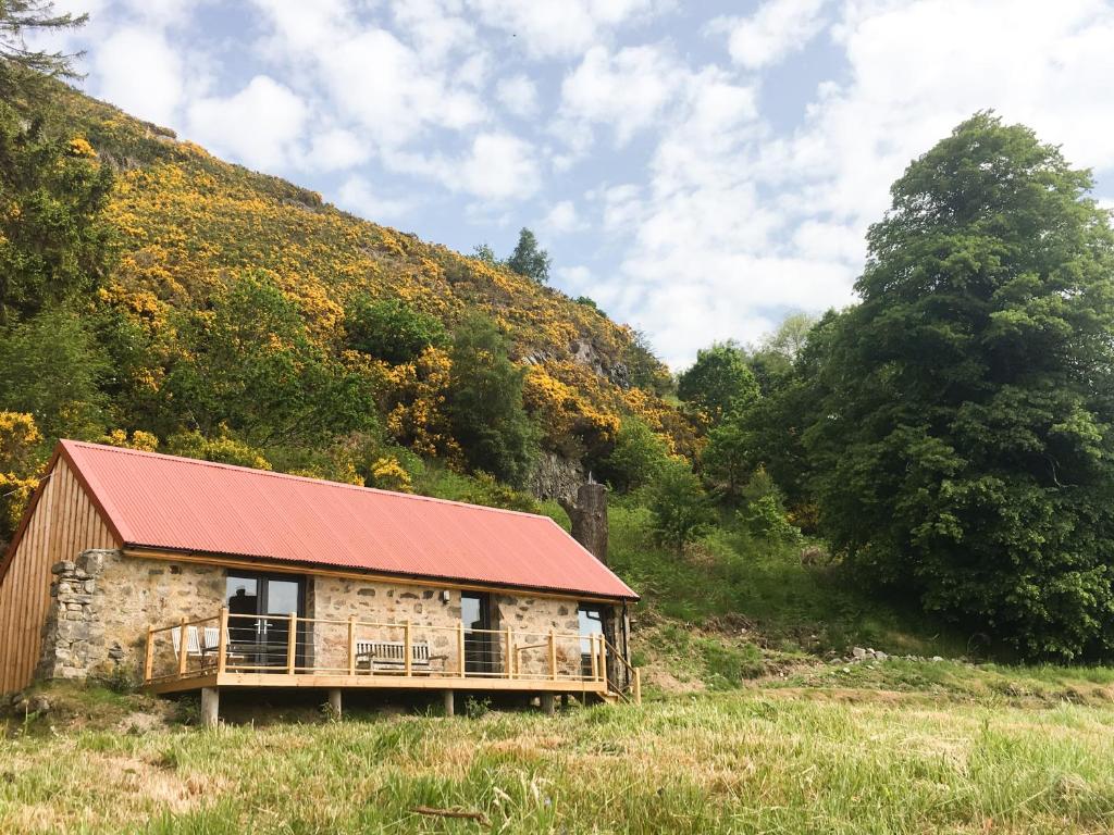 een gebouw met een rood dak op een heuvel bij East Craigdhu Cow Byre in Beauly