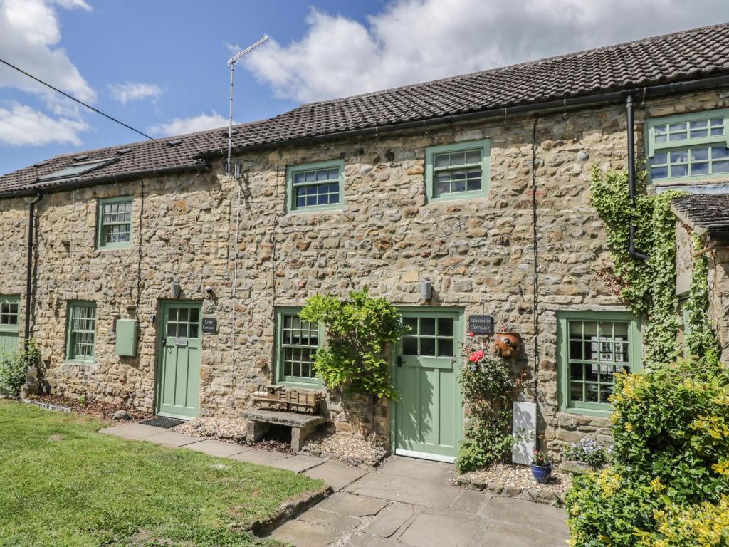 an old stone house with green doors and windows at Edmunds Cottage in Bedale