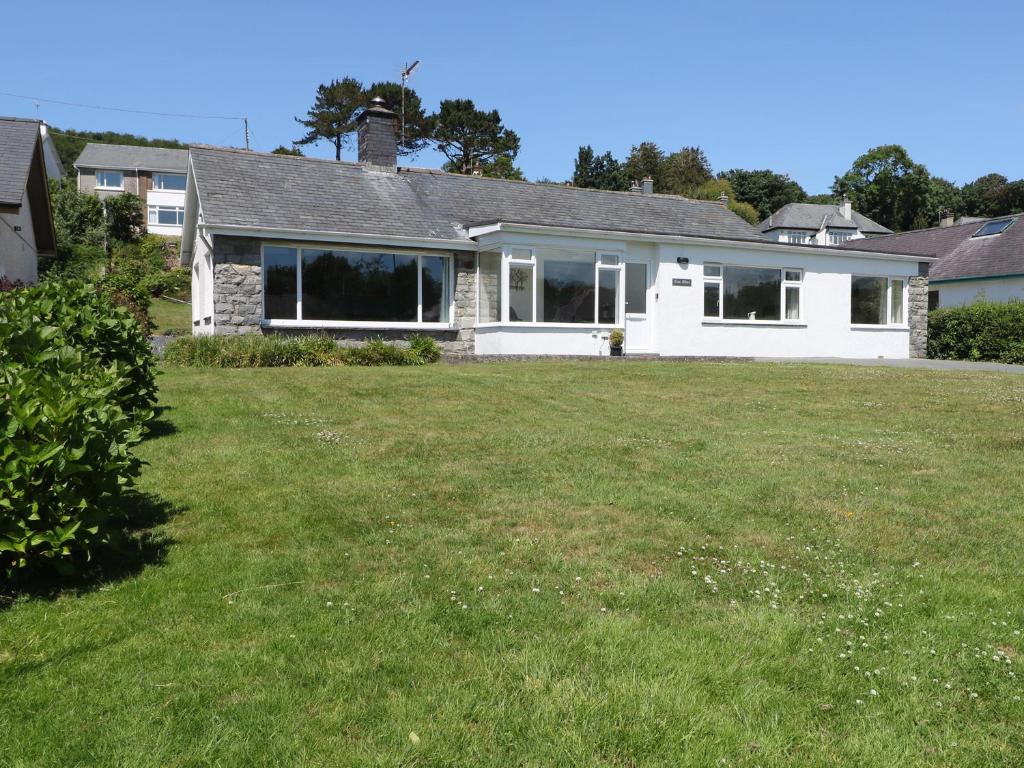 a house with a large lawn in front of it at Cae Glas in Pwllheli