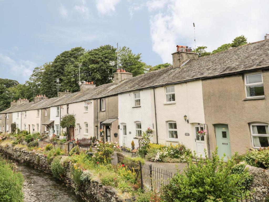 eine Reihe von Häusern neben einem Fluss in der Unterkunft Herdwick Cottage in Grange Over Sands