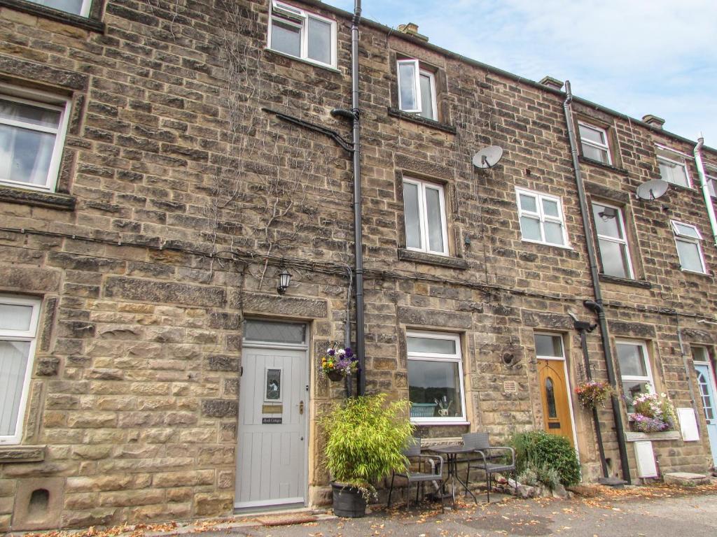 a brick building with a white door and a table at Rock Cottage in Bakewell