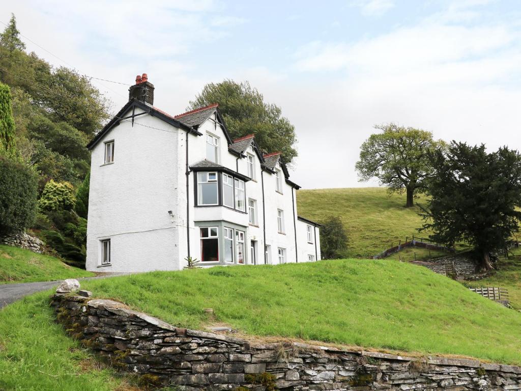 a white house on a hill with a stone wall at Low Skelgill in Windermere