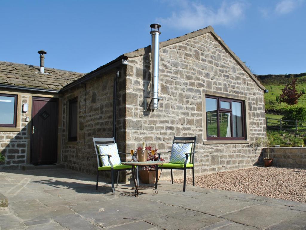 a table and chairs in front of a stone house at Baywood Cottage in Keighley