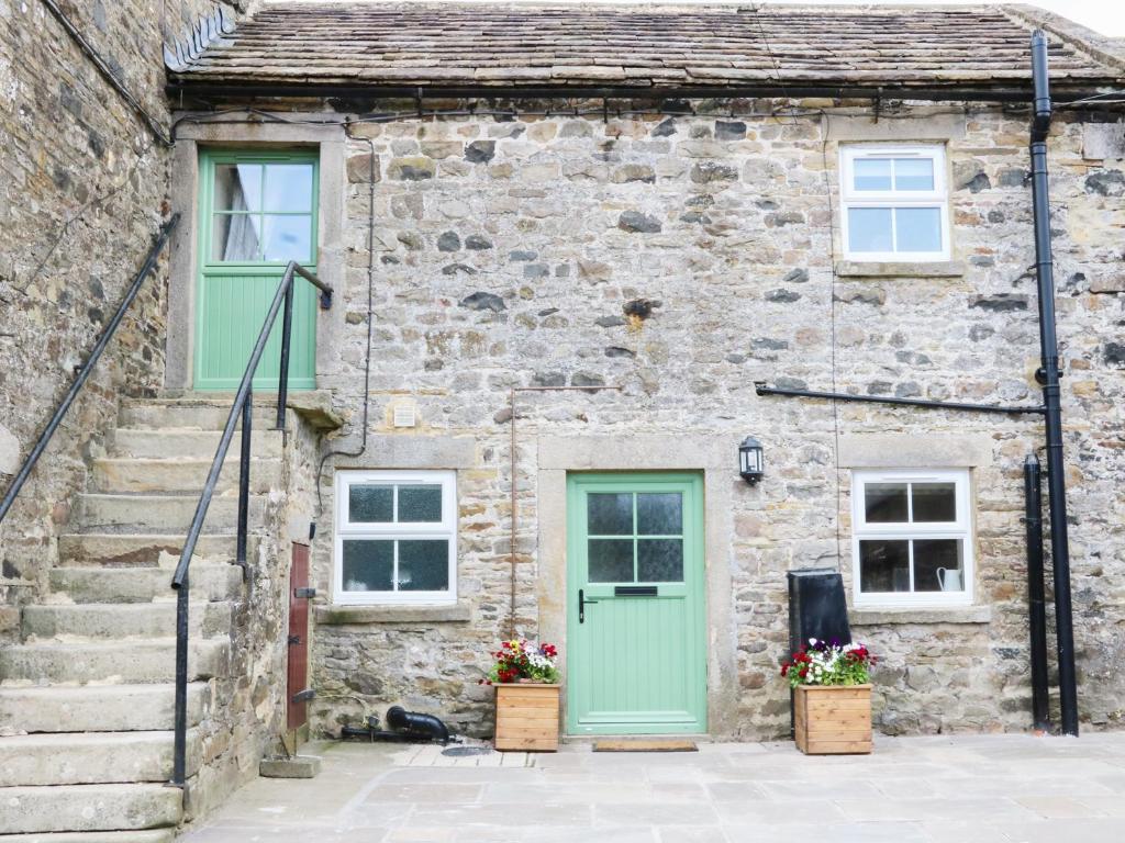 an old stone house with green doors and stairs at The Stables in Barnard Castle