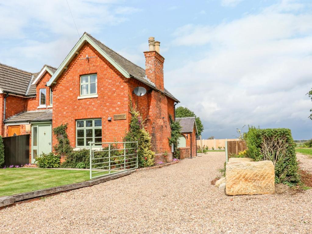 a red brick house with a gravel driveway at Chippers Cottage in Woodhall Spa