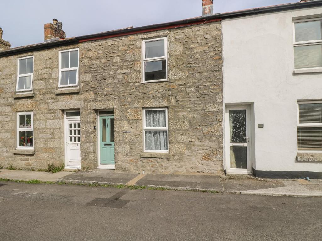 a stone house with white doors and windows at Mollys Cottage in St. Just