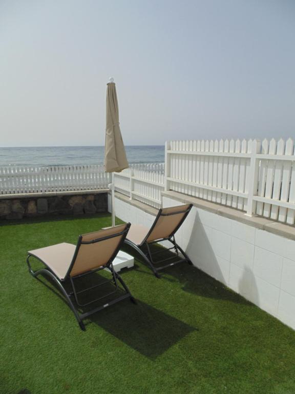 dwa krzesła i parasol na balkonie z widokiem na ocean w obiekcie Bungalows Miami Beach w mieście San Agustin