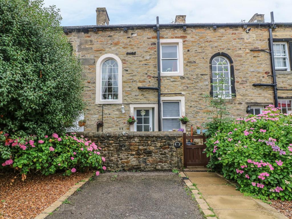 una vieja casa de piedra con flores delante en Daisy's Holiday Cottage en Skipton