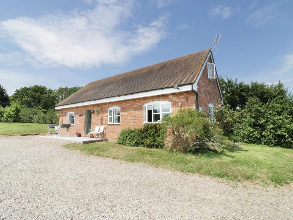 a brick house with a roof on a gravel road at The Hen House in Bromyard