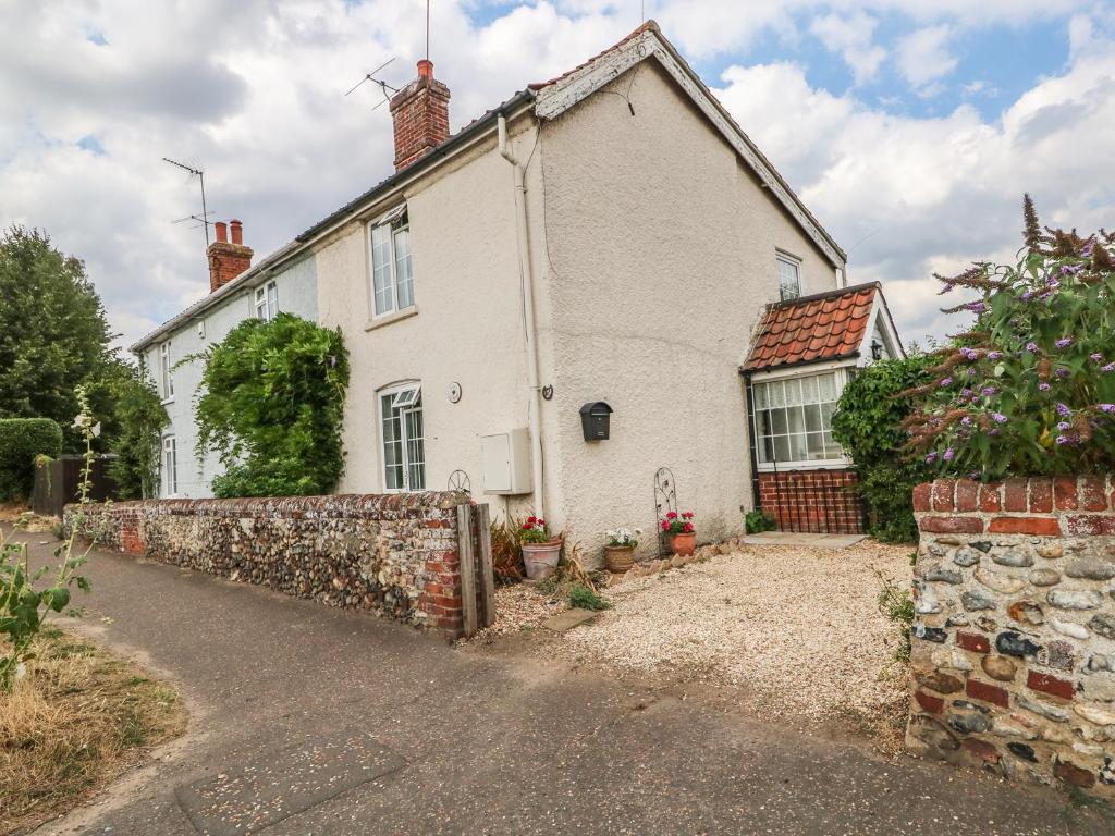 a white house with a stone wall in front of it at Megs Cottage in Norwich