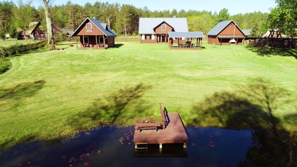 um grupo de chalés num campo com um lago em Dzūkijos uoga em Viršurodukis