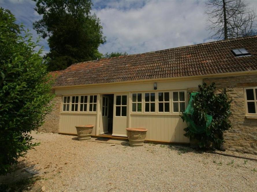 a small house with a garage with windows at Upper Mill Barn in Quenington